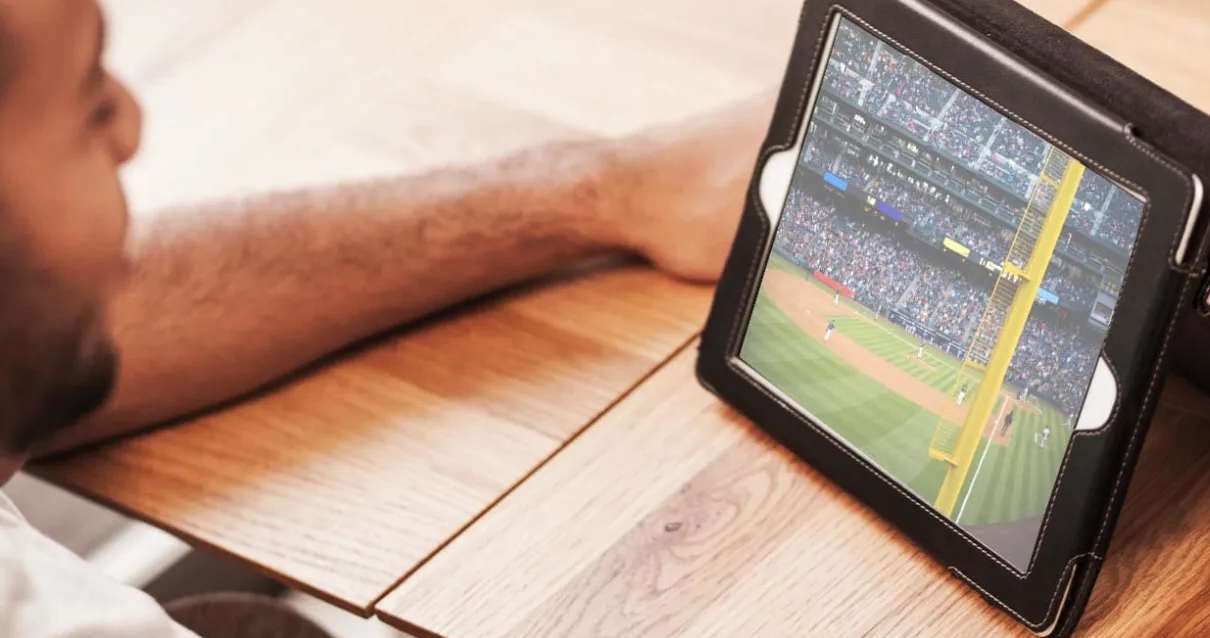 Stock image of someone watching a baseball game on their computer.