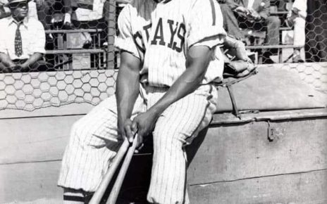 Josh Gibson sitting on a bench in his Homestead Grays uniform.