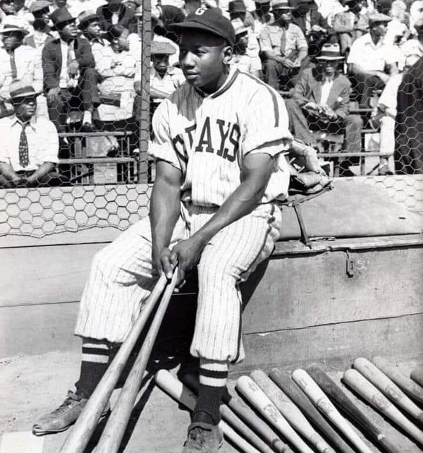 Josh Gibson sitting on a bench in his Homestead Grays uniform.